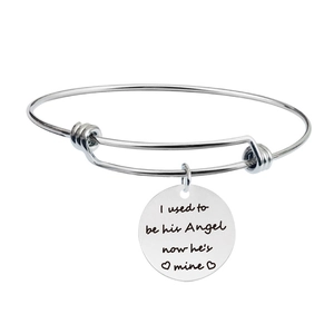 Macro detail of silver adjustable stainless steel bracelet with engraved circular pendant