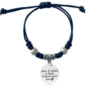 Detail of woven rope bracelet featuring paw print pendant and engraved sentiment charm