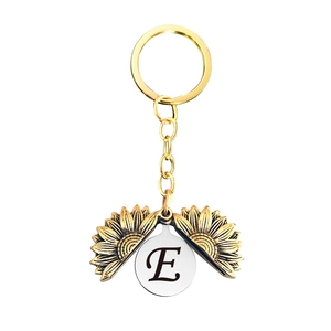 Détail du porte-clés tournesol doré ouvrant avec la lettre E gravée à l'intérieur