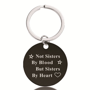 Macro detail of black metal keychain with engraved Not Sisters By Heart quote