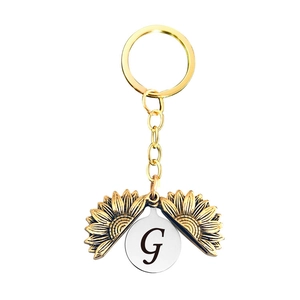 Détail macro du porte-clés tournesol doré avec le médaillon gravé de la lettre G