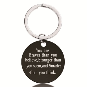 Macro detail of black stainless steel pendant keychain with engraved motivational quote