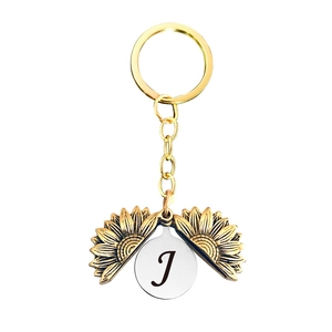 Détail du porte-clés médaillon tournesol avec lettre J gravée sur le disque argenté