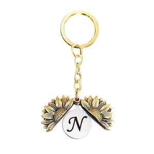 Détail d'un porte-clés tournesol doré avec médaillon ouvrant et lettre N personnalisée