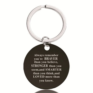 Detail of round black stainless steel keychain with engraved inspirational quote text
