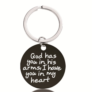 Detail of matte black stainless steel keychain with engraved memorial text on white background