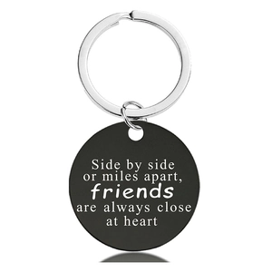 Detail view of a black round stainless steel keychain with laser engraved friendship quote