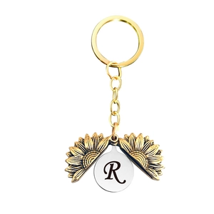 Détail du porte-clés tournesol doré ouvrant avec gravure lettre R sur disque en argent