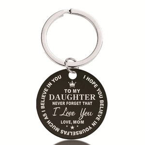 Detail of round black stainless steel keychain with engraved quote and crown symbol