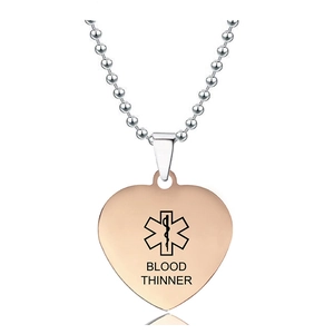 Primer plano del colgante médico de corazón en oro rosa con estrella de vida y grabado