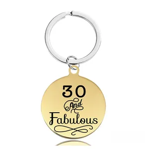 Détail d'un porte-clés doré rond avec gravure 30 And Fabulous et anneau argenté