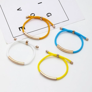 Detail of four colorful braided rope bracelets with rose gold metal tubes on white background