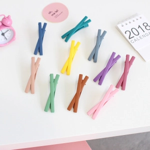 Detailed macro view of X-shaped matte hair clips in ten assorted chic autumn colors
