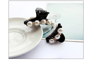 Dettaglio di eleganti mollette nere per capelli con perle bianche e strass dorati
