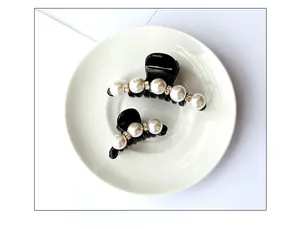 Dettaglio di eleganti mollette nere per capelli con perle bianche e piccoli strass