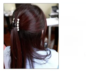 Dettaglio di un fermaglio nero per capelli con perle finte indossato da una modella