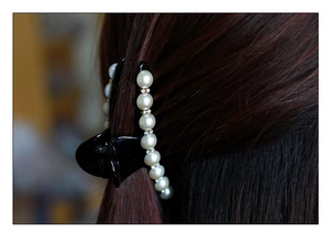 Dettaglio di una pinza per capelli nera con perle eleganti e strass brillanti