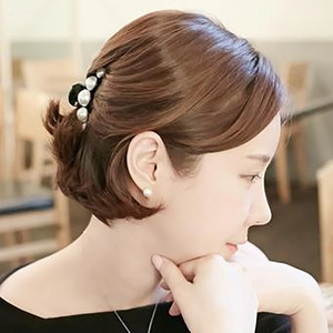 Elegante molletta per capelli nera con perle bianche indossata da una modella al caffè