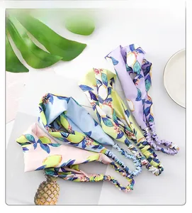Detail view of four-color floral knot headbands in pink, blue, yellow, and purple silk fabric