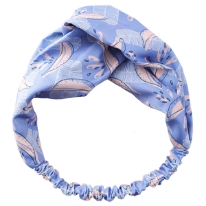 Tropical banana leaf print headband with cross-knot design on a light blue fabric background
