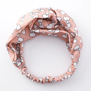 Rosa Satin-Stirnband mit weißem Schleifenmuster und Gummizug auf weißem Grund
