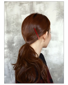 Nahaufnahme einer minimalistischen roten Haarklammer an einem Modell mit braunem Haar