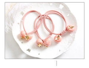 Détail de trois élastiques à cheveux roses avec pendentifs fraise et pêche en 3D