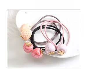 Détail d'élastiques à cheveux fraise avec étoiles dorées sur une assiette blanche