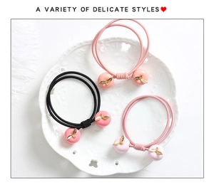 Vue détaillée d'élastiques à cheveux avec pendentifs cerise et pomme sur un plateau