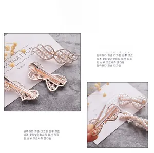 Macro view of crystal and pearl encrusted metal bow and feather duckbill hair clips