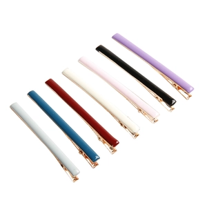 Set mit sieben minimalistischen bunten Emaille-Haarspangen mit goldener Metallbasis auf Weiß