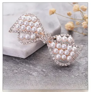 Detailed view of elegant bow hair clip with white pearls and sparkling rhinestones