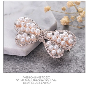Detail of elegant bow hair clip with white faux pearls and sparkling rhinestones