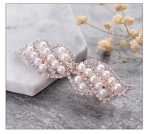 Detail of rose gold hair clip with sparkling rhinestones and elegant white pearls