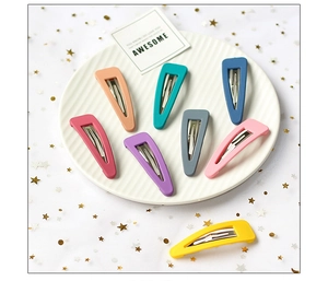 Detail view of eight colorful matte BB hair clips in a white porcelain dish with gold stars