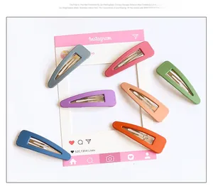 Detailed view of six colorful matte finish triangular snap hair clips on white background