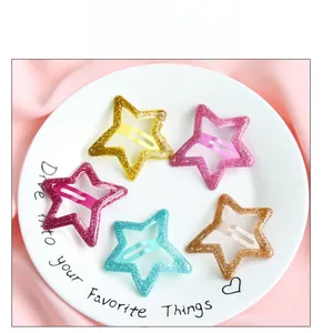 Détail de cinq barrettes étoiles à paillettes colorées sur une assiette en céramique