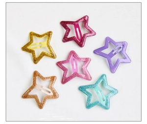 Détail de six barrettes étoiles colorées à paillettes dorées, roses et violettes