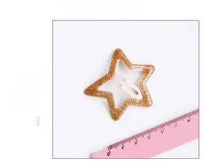 Vue détaillée d'une pince à cheveux étoile évidée de 4 cm avec paillettes dorées