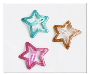 Détail de barrettes étoiles à paillettes en bleu, marron et rose pour filles