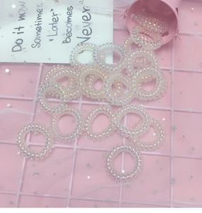 Nahaufnahme holografischer Spiral-Haargummis auf rosa Netzstoff mit Glanzeffekt