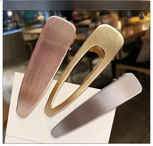 Détail de barrettes en métal brossé mat en finitions or rose, doré et argenté