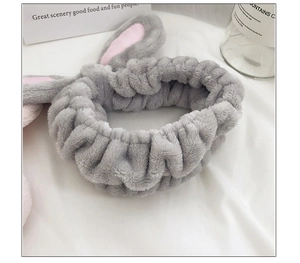 Close-up of soft grey plush bunny ear headband with pink inner lining for skincare