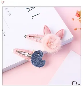 Détail de pinces à cheveux pompon oreilles de lapin rose et motif poussin bleu tricoté