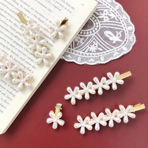 Elegant white pearl flower hair clips on gold base over vintage aesthetic background