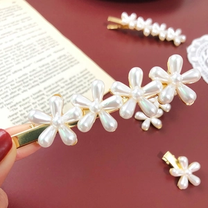 Close-up of pearl flower hair clips with golden base on a vintage lace background