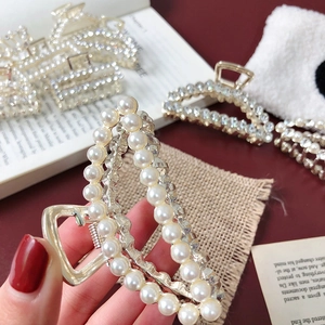 Luxury pearl rhinestone hair claw clip with gold metal finish shown in hand