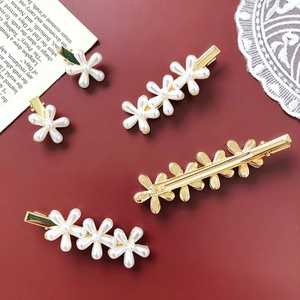 Detailed set of pearl daisy hair clips with gold alloy base on a vintage red backdrop