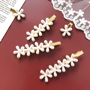 Detailed view of elegant pearl flower hair clips on a dark red background