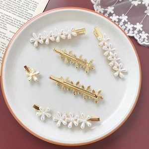 Detailed close-up of mini pearl flower hair clips in various sizes on a ceramic plate
